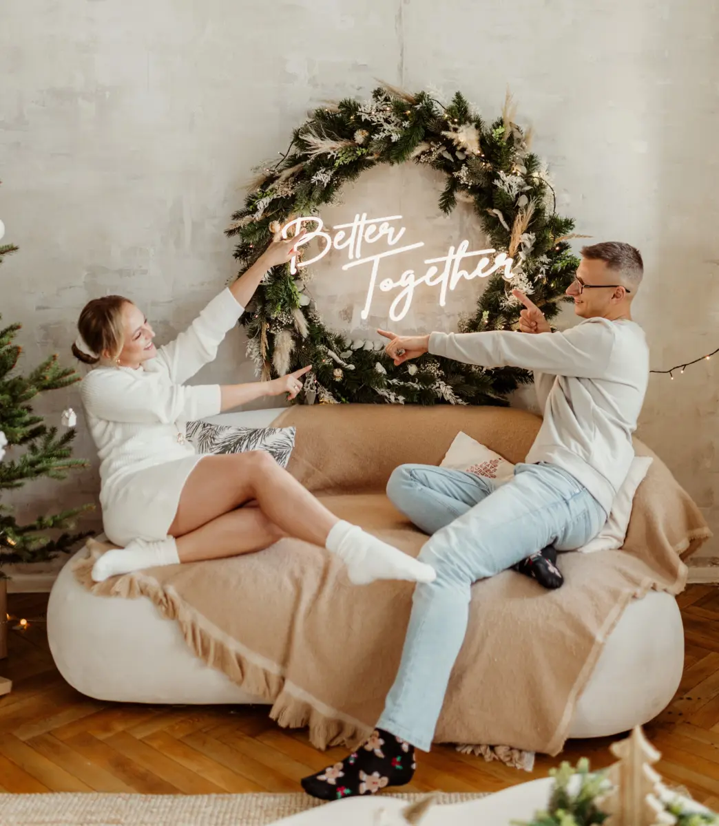 Neon LED o treści "Better together" , na który palcami wskazują mężczyzna i kobieta